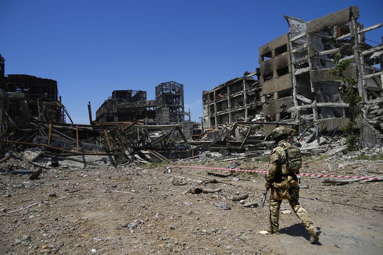 Un soldado ruso camina frente a la planta metalúrgica de Azovstal, en Mariupol, este de Ucrania, el 13 de junio de 2022. (Foto AP)