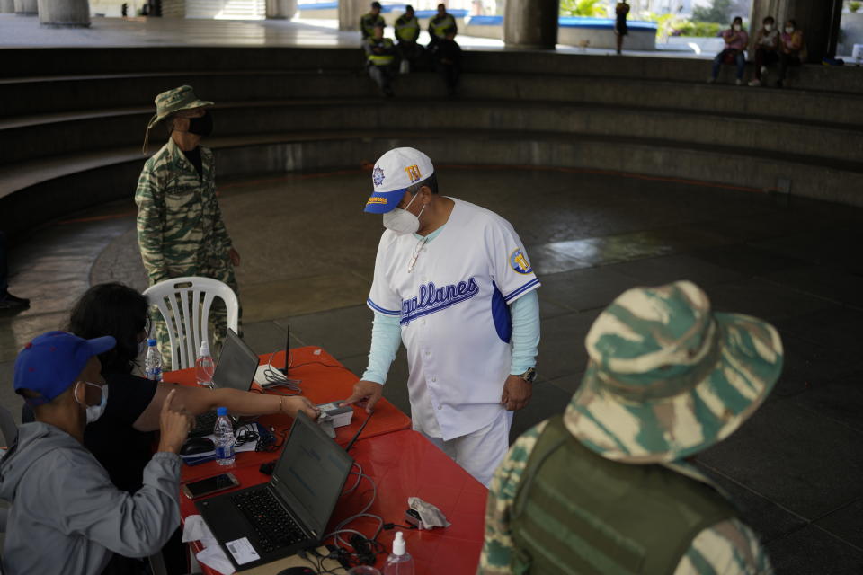 A man gives his fingerprint at a table set up by the National Election Council (CNE) where people can sign a petition in favor of holding a referendum to remove President Nicolas Maduro from office in Caracas, Venezuela, Wednesday, Jan. 26, 2022. The signatures of 20 percent of registered voters must be collected in 12 hours to activate a presidential recall, a one rule that Maduro's opposition criticizes as impossible. (AP Photo/Matias Delacroix)