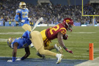 Southern California running back Darwin Barlow, right, dives in for a touchdown as UCLA defensive back Jaylin Davies, lower left, defends along with defensive back Kenny Churchwell III during the second half of an NCAA college football game Saturday, Nov. 19, 2022, in Pasadena, Calif. (AP Photo/Mark J. Terrill)