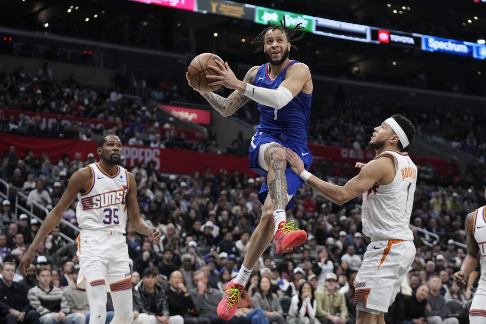 Los Angeles Clippers guard Amir Coffey, center, shoots as Phoenix Suns forward Kevin Durant, left, and guard Devin Booker defend during the second half of an NBA basketball game Monday, Jan. 8, 2024, in Los Angeles. (AP Photo/Mark J. Terrill)