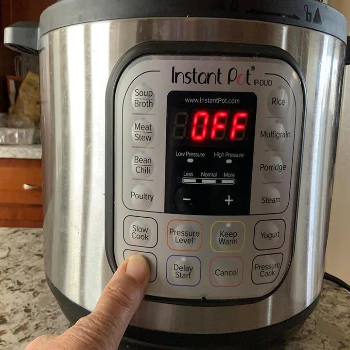 reviewer pressing the saute button on the cooker. there are also buttons for things like soup, poultry, slow cook, rice, yogurt, and porridge