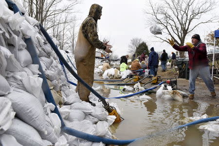 Volunteers set up a wall of sandbags and series of pumps to create a barricade preventing the rising water from flooding a home after several days of heavy rain in Arnold, Missouri, December 30, 2015. REUTERS/Kate Munsch