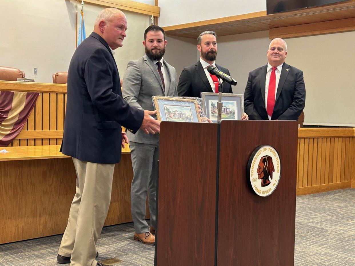 Toms River Mayor Mo Hill (left) presents paintings of town hall to outgoing Councilmen Josh Kopp and Matt Lotano, while Councilman Kevin Geoghegan looks on.