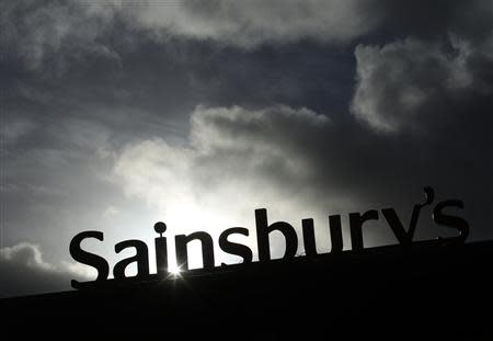 A Sainsbury's sign is seen silhouetted outside a supermarket at Pulborough, southern England January 8, 2014. British grocer J Sainsbury reported its "best Christmas ever" on Wednesday but warned that consumers were likely to tighten their belts in the early part of 2014 and cut its sales growth forecast accordingly. REUTERS/Luke MacGregor