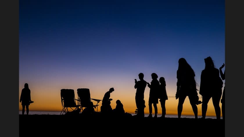 Beachgoers are cast in silhouette after the last rays of sunlight escape into the night on Santa Monica Beach on Wednesday.