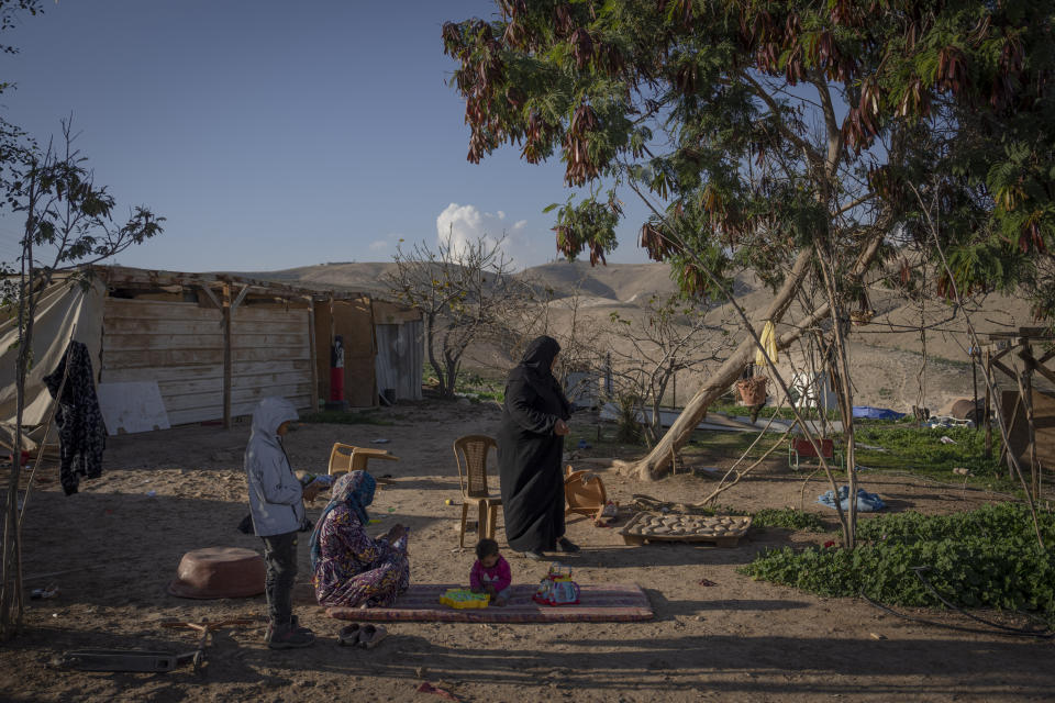 A Bedouin woman play with her child at the West Bank hamlet of Khan al-Ahmar, Sunday, Jan. 22, 2023. The long-running dispute over the West Bank Bedouin community of Khan al-Ahmar, which lost its last legal protection against demolition four years ago, resurfaced this week as a focus of the frozen Israeli-Palestinian conflict. Israel's new far-right ministers vow to evacuate the village as part of a wider project to expand Israeli presence in the 60% of the West Bank over which the military has full control. Palestinians seek that land for a future state. (AP Photo/Oded Balilty)