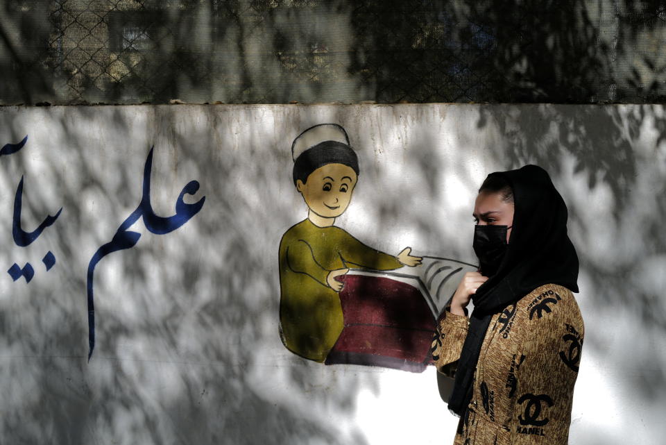 An 11th grade secondary school student walks past her former school in Kabul, Afghanistan.