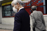 A man wears a mask in front of an electronic stock board showing Japan's Nikkei 225 index at a securities firm in Tokyo Thursday, May 28, 2020. Asian stocks are mixed after an upbeat open, as hopes for an economic rebound from the coronavirus crisis were dimmed by tensions between the U.S. and China over Hong Kong and other issues. (AP Photo/Eugene Hoshiko)
