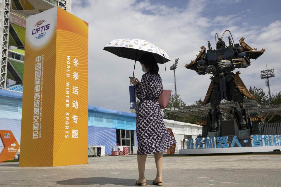 A visitor stands near a giant robot sculpture displayed at the venue for the China International Fair for Trade in Services (CIFTIS) to be held in Beijing on Friday, Sept. 4, 2020. As China recovers from the COVID-19 pandemic, business as usual is picking back up with the holding of the China International Fair for Trade in Services. Nearly 2,000 Chinese and foreign enterprises will participate and showcase their newest technology in public health and digital technology (AP Photo/Ng Han Guan)