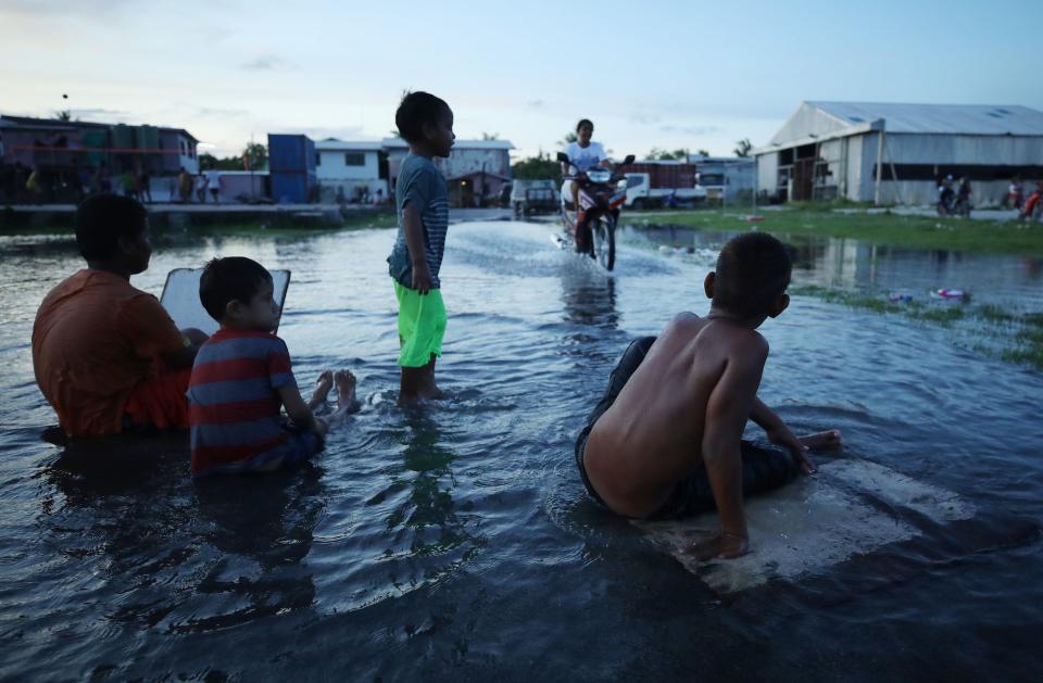 Boys play in floodwaters occurring around high tide in a low lying area near the airport on November 27, 2019 in Funafuti, Tuvalu.