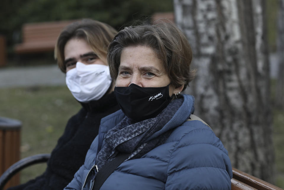 A Turkish mother and her son wearing masks with the signatures of Turkey's founder Mustafa Kemal Ataturk to help protect against the spread of coronavirus, sit in a deserted public garden during a lockdown, in Ankara, Turkey, Saturday, Jan. 9, 2021. Turkey impose a two-day lockdown on the weekend, in a bid to stem the spread of COVID-19.(AP Photo/Burhan Ozbilici)