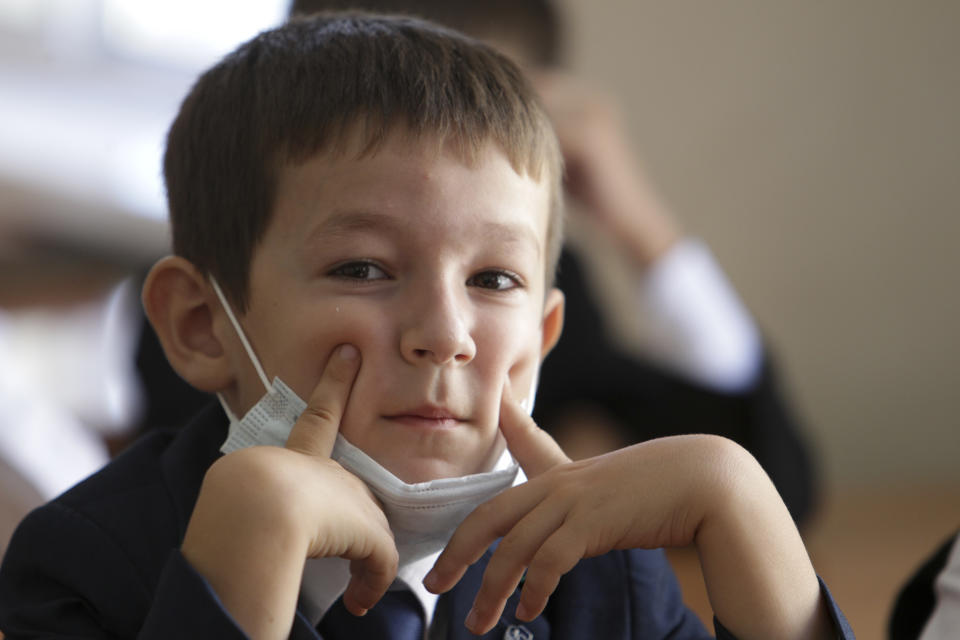 A boy wearing a face mask to protect against coronavirus sits in a classroom during a ceremony marking the start of classes at a school as part of the traditional opening of the school year known as "Day of Knowledge" in Grozny, Russia, Tuesday, Sept. 1, 2020. Across the country, schools start their usually festive opening day on Sept. 1. (AP Photo/Musa Sadulayev)