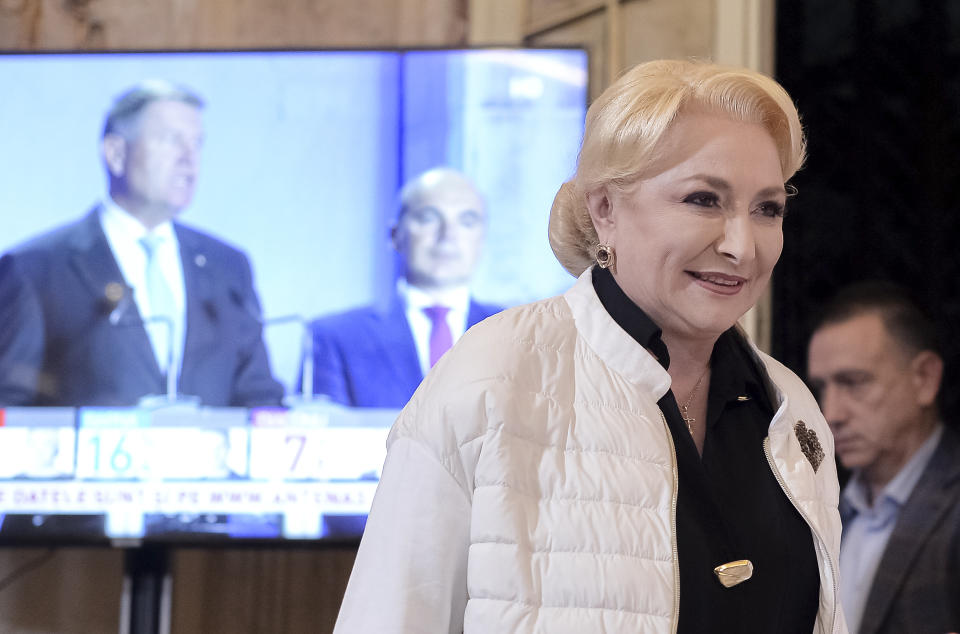 Former Romanian Prime Minister Viorica Dancila smiles before a statement after exit polls indicate her as the runner up of the presidential race, with up to 25 percent of the votes in Bucharest, Romania, Sunday, Nov. 10, 2019. Dancila will face incumbent President Klaus Iohannis, seen on the the left on screen, in an election runoff on Nov. 24. (AP Photo/Alexandru Dobre)