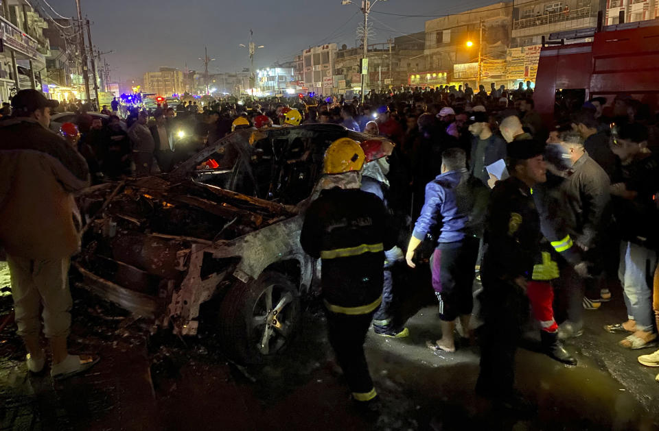 Civil defense members gather at the site of a burned vehicle targeted by a U.S. drone strike in east Baghdad, Iraq, Wednesday, Feb. 7, 2024. (AP Photo/Hadi Mizban)