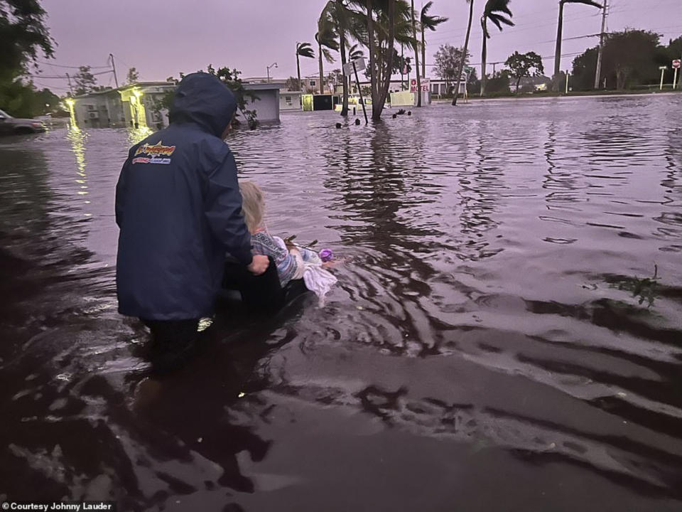 In this photo provided by Johnny Lauder, Lauder's mother, Karen Lauder, 86, is pushed through floodwaters in a wheelchair after being rescued from her home, in Naples, Fla., Wednesday, Sept. 28, 2022, following Hurricane Ian. (Courtesy of Johnny Lauder via AP)