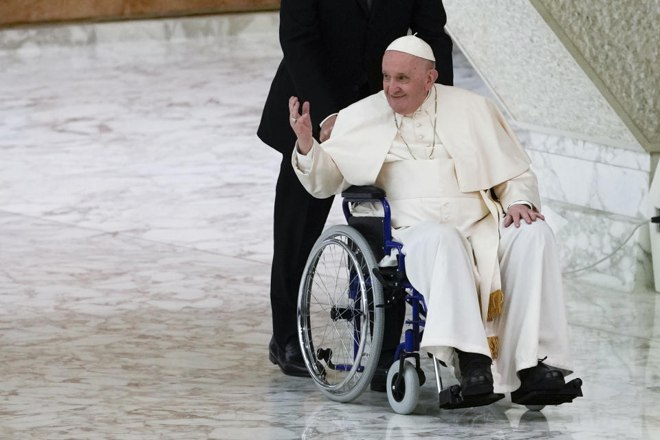 Pope Francis arrives in a wheelchair to attend an audience with nuns and religious superiors in the Paul VI Hall at The Vatican, Thursday, May 5, 2022. Francis, 85, has been suffering from strained ligaments in his right knee for several months. He revealed he recently received some injections to try to relieve the pain, but he has continued to struggle to walk and stand. (AP Photo/Alessandra Tarantino)