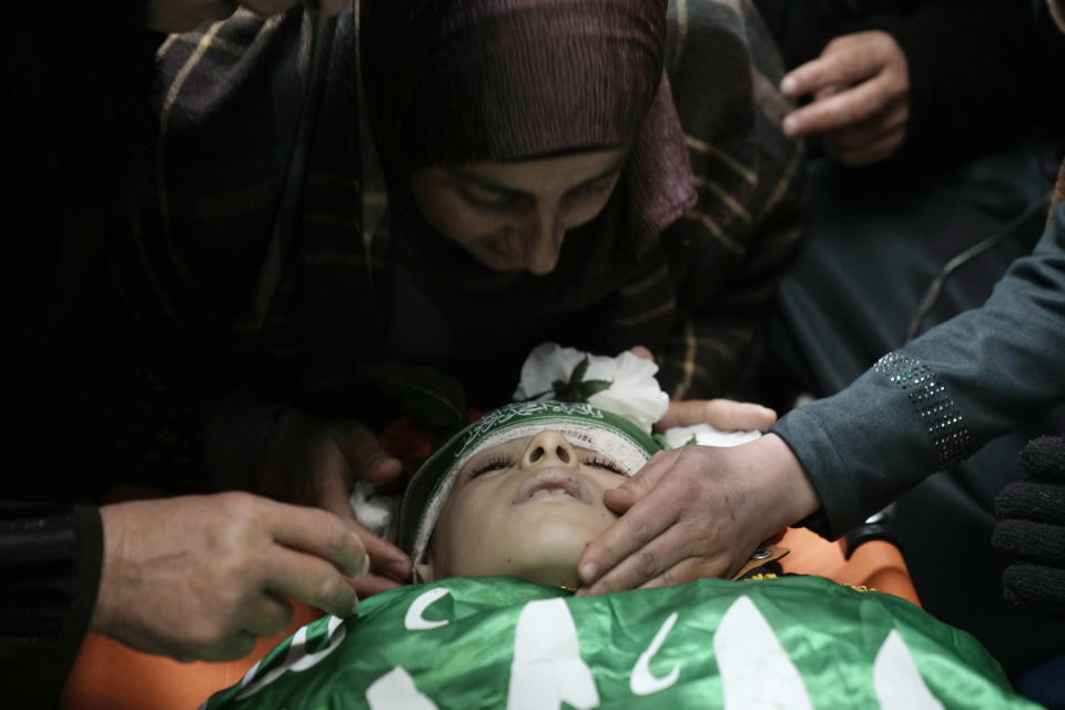 The mother of Amr al-Najjar, 11, draped in the Hamas flag, center, weeps during his funeral in the West Bank village of Burin, near Nablus, Tuesday, March 5, 2024. Palestinian media reports that he was shot during an Israeli military incursion into the village of Burin. The Israeli military says they opened fire in the village and are aware of reports of a minor being killed. (AP Photo/Majdi Mohammed)