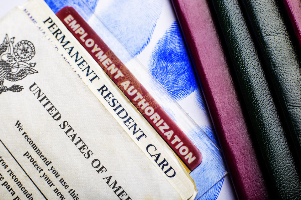 USA permanent resident card (Green Card) with Employment Authorization card next to passports and fingerprints