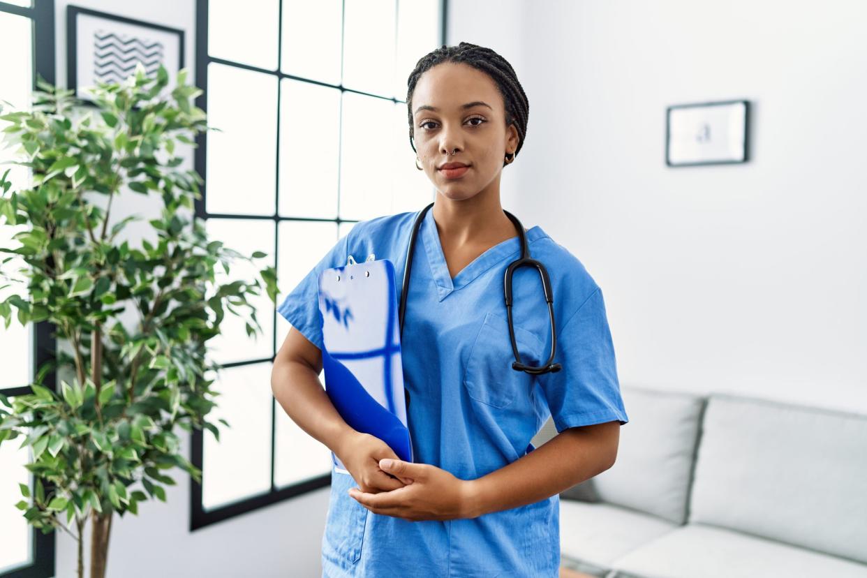 Young african american woman working wearing doctor uniform working at the clinic thinking attitude and sober expression looking self confident