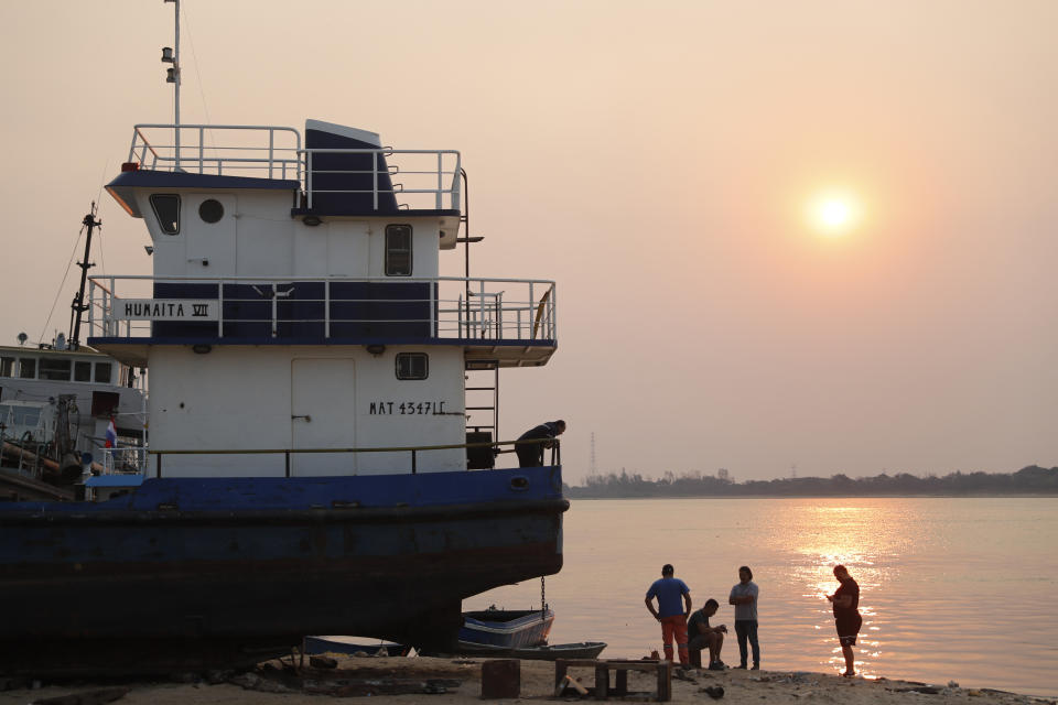 Los trabajadores descansan al atardecer en la orilla del Río Paraguay en Asunción, Paraguay, el miércoles de octubre de 2020. (AP Foto/Jorge Saenz)