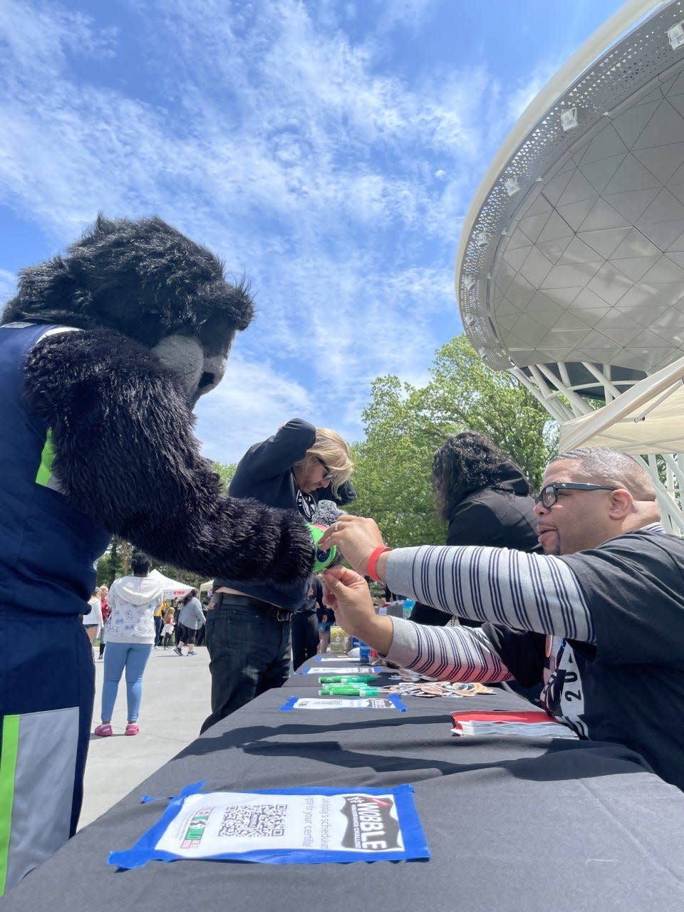 Longtime IMMAWII volunteer Terrance Butts puts a wrist band on the Iowa Wolves mascot who turned out to support the Wobble world record attempt Saturday.