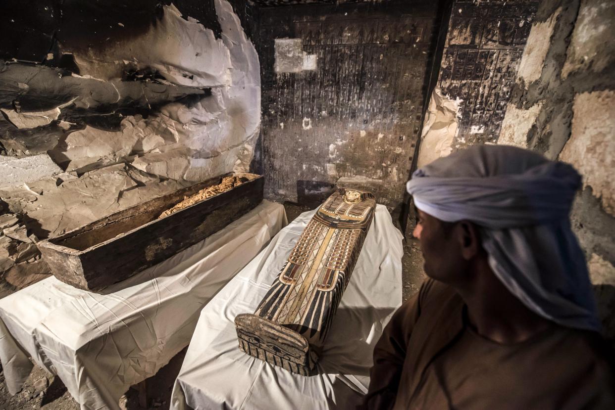 An Egyptian worker standing next to an opened intact sarcophagus containing a well-preserved mummy of a woman named "Thuya" wrapped in linen. (Photo: KHALED DESOUKI via Getty Images)