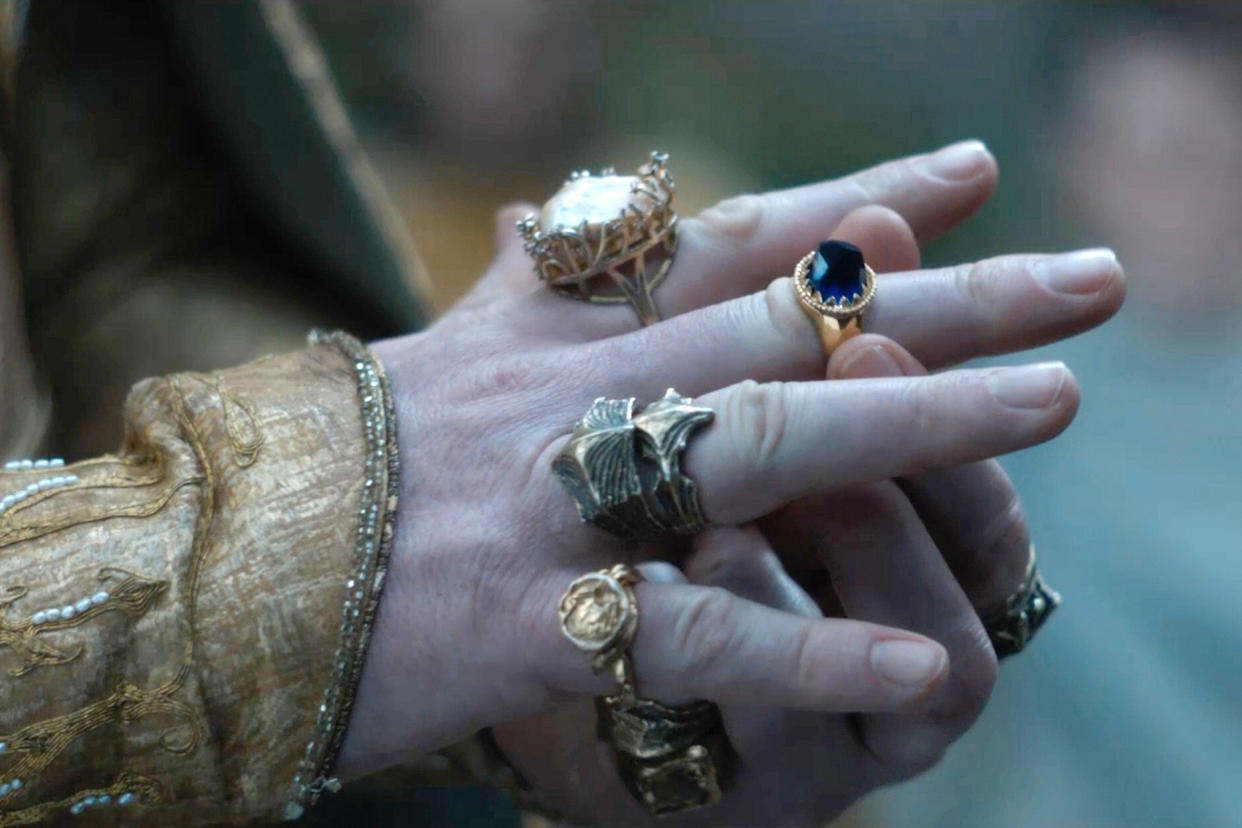 A hand wearing several rings.