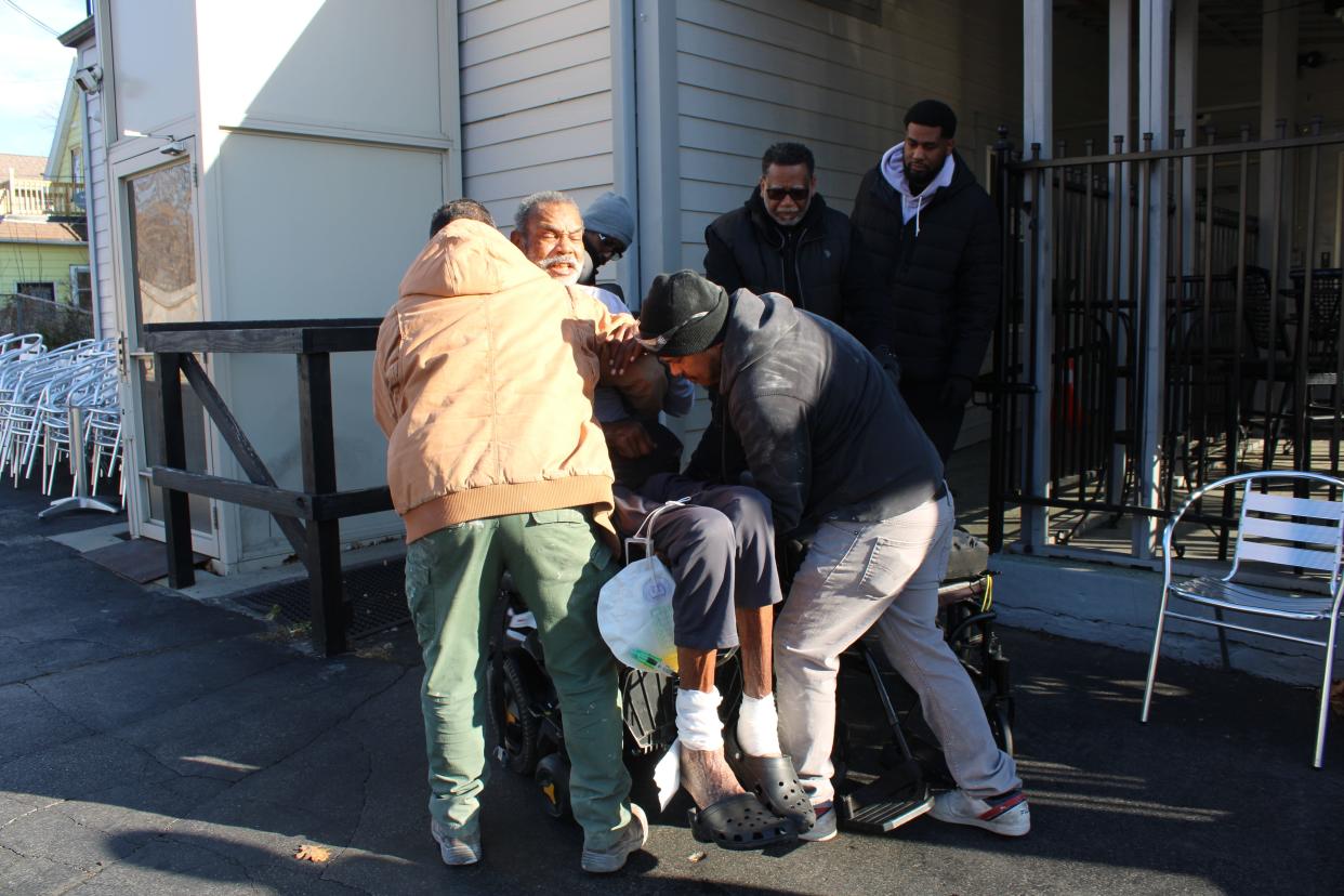 Jewel Currie is lifted into his motorized wheelchair by a group of friends.