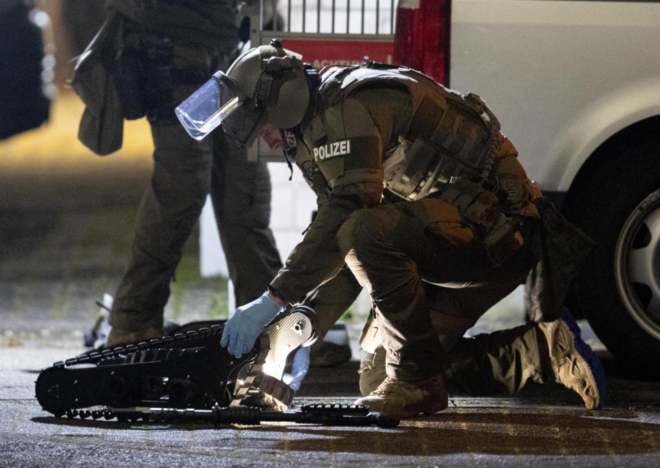 A special forces officer works on a robot in front of a house that is searched through by police in Hanau, Germany Thursday, Feb. 20, 2020. Eight people were killed in shootings in and outside two hookah lounges in a southwestern German city late Wednesday, and authorities were searching for the perpetrators. (AP Photo/Michael Probst)