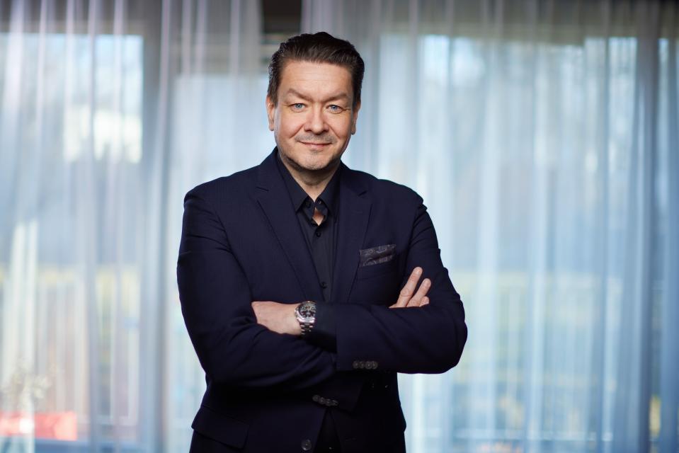 Birgir Jónsson, CEO of Play, wears a navy suit and black shirt with his arms crossed.