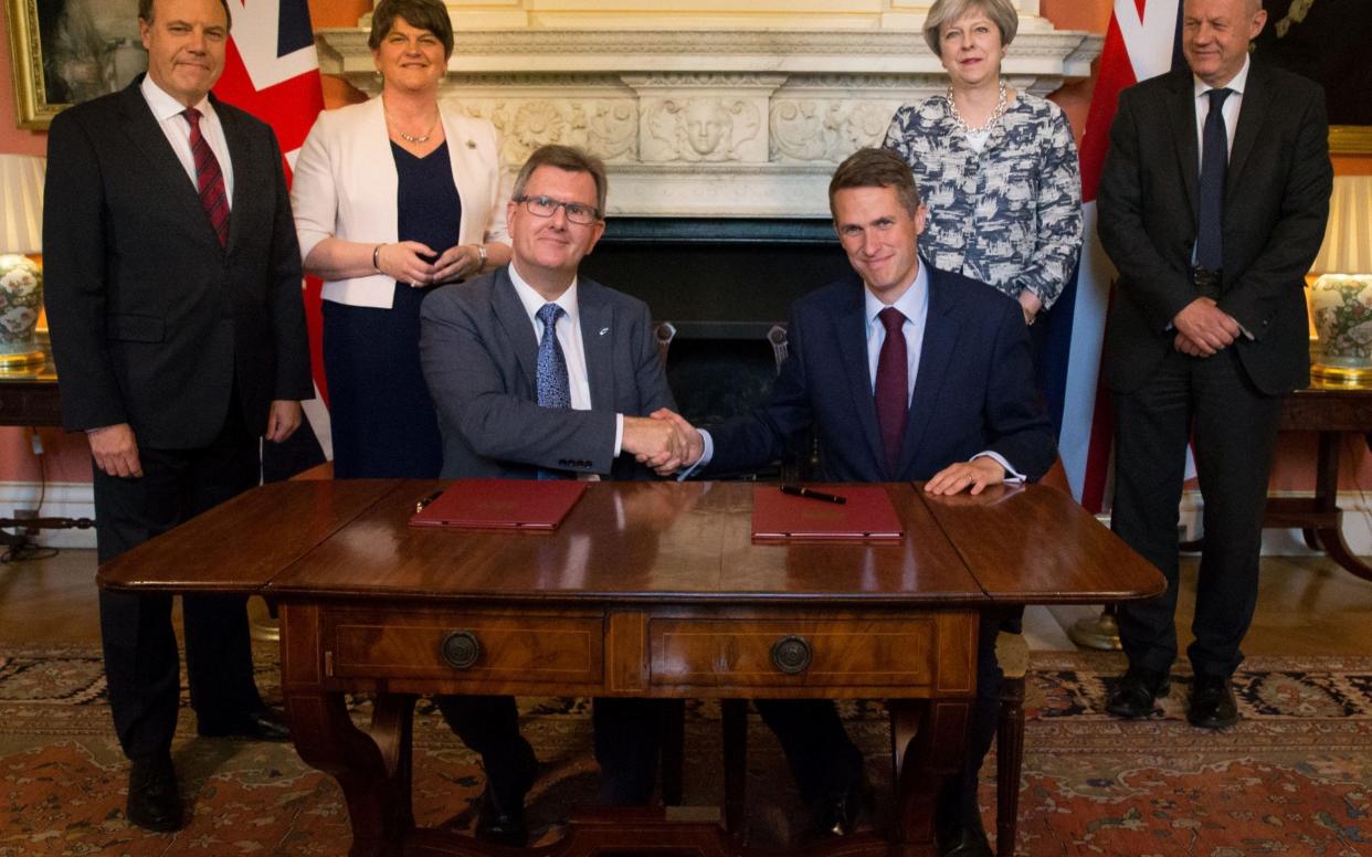 Sir Jeffrey Donaldson and Gavin Williamson agree the historic agreement. Theresa May is at the back - PA