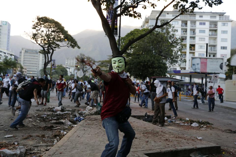 An anti-government protester fires a slingshot during clashes at Altamira square in Caracas