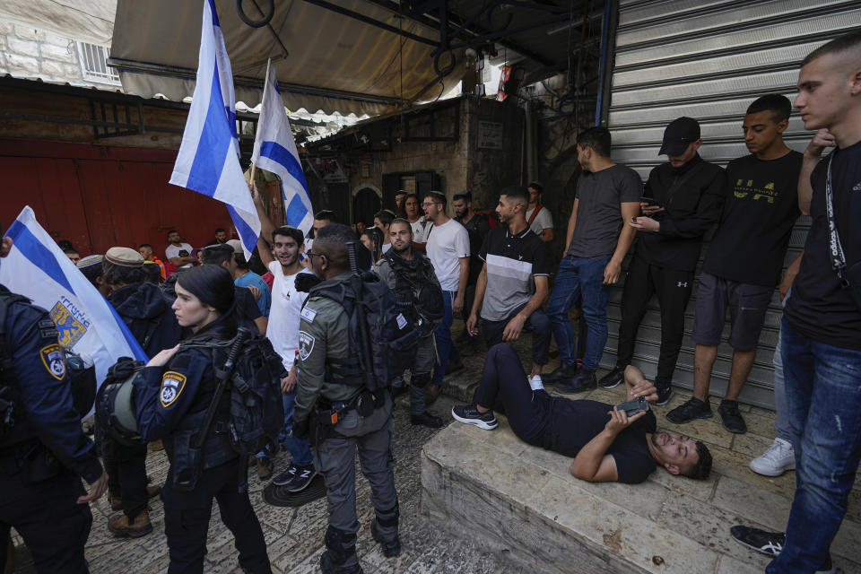 Palestinians, right, look on as Israelis wave national flags during a march marking Jerusalem Day, in Jerusalem's Old City, Thursday, May 18, 2023. The parade was marking Jerusalem Day, an Israeli holiday celebrating the capture of east Jerusalem in the 1967 Mideast war. Palestinians see the march as a provocation. (AP Photo/Ohad Zwigenberg)