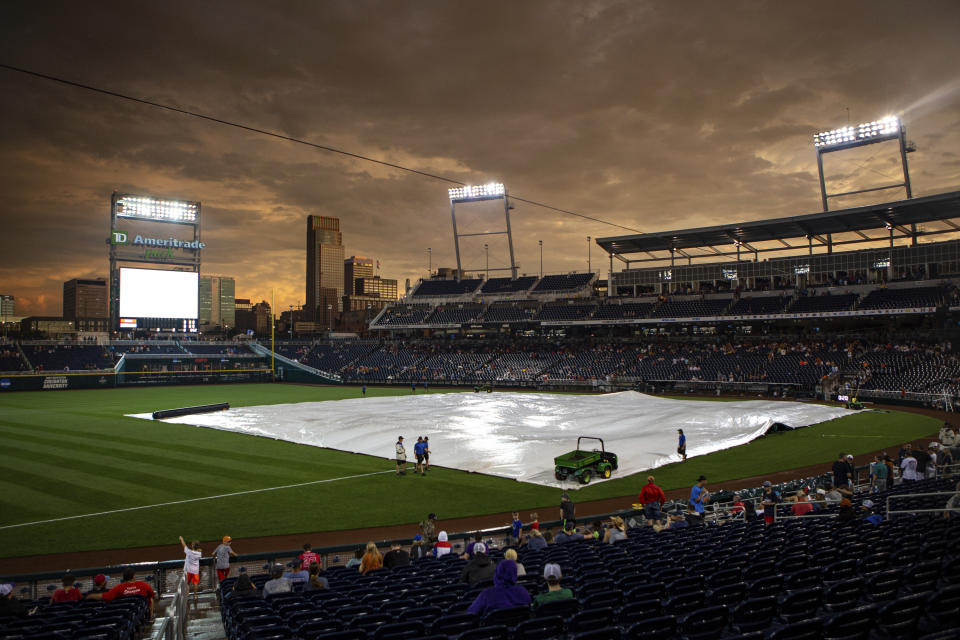 Grounds crew start to gather to remove the tarp to get the field ready for the game between Virginia and Texas in the College World Series Thursday, June 24, 2021, at TD Ameritrade Park in Omaha, Neb. (AP Photo/John Peterson)