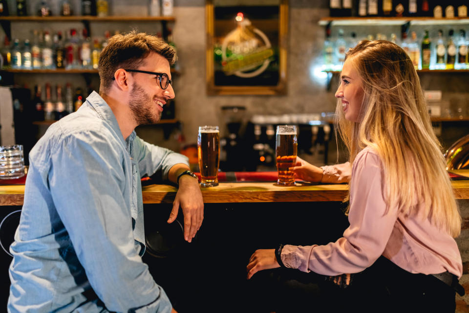 A man and woman sit and have drinks together at a bar