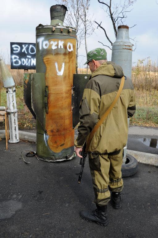 A pro-Russian separatist fighter stands in front of part of a ballistic missile on October 21, 2014, in Donetsk, Ukraine