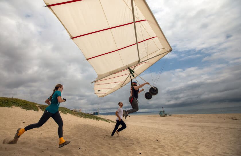 Playa Del Rey,, CA - June 11: Kim Wright, left, and gliding instructor Adam Zachary Smith, middle, help students hang glide off the bluff on Sunday, June 11, 2023, at Dockweiler Beach in Playa Del Rey, CA. (Francine Orr / Los Angeles Times)