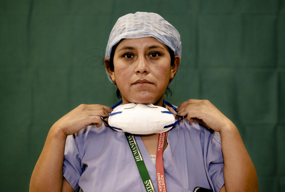 Ana Travezano, 39, a nurse at the Humanitas Gavazzeni Hospital in Bergamo, Italy poses for a portrait at the end of her shift Friday, March 27, 2020. The intensive care doctors and nurses on the front lines of the coronavirus pandemic in Italy are almost unrecognizable behind their masks, scrubs, gloves and hairnets. But the thin battle armor donned at the start of each shift is their only barrier to contagion. (AP Photo/Antonio Calanni)