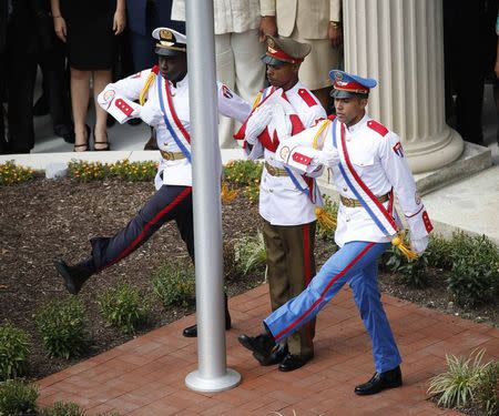 The Cuban flag is carried out of the Cuban Embassy by an honor guard during an official ceremony in Washington July 20, 2015. The Cuban flag was raised over Havana’s embassy in Washington on Monday for the first time in 54 years as the United States and Cuba formally restored relations, opening a new chapter of engagement between the former Cold War foes. REUTERS/Gary Cameron