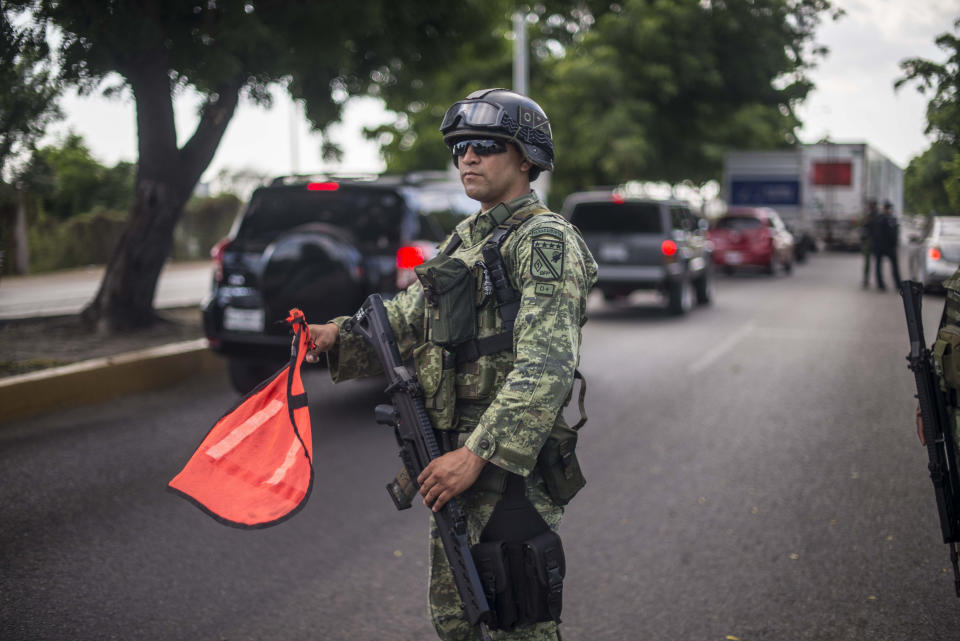 Mexican soldiers stand guard at a checkpoint on the road to the municipality of Novalto, near Culiacan Mexico, Saturday, Oct. 26, 2019. Six 24/7 checkpoints have been set up on the main entrances to the city of Culiacan, to search for weapons or contraband. (AP Photo/Augusto Zurita)