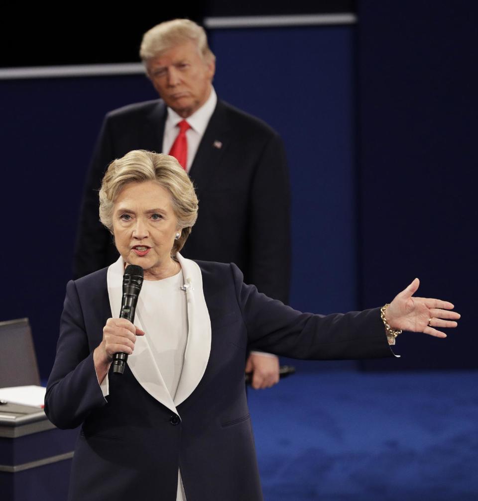 FILE - In this Sunday, Oct. 9, 2016, file photo, Republican presidential nominee Donald Trump listens to Democratic presidential nominee Hillary Clinton during the second presidential debate at Washington University in St. Louis. Clinton has a lot of plans for 2017, including some reflections on her stunning loss to Donald Trump. The former secretary of state, senator and first lady is working on a collection of personal essays that will touch upon the 2016 presidential campaign, Simon & Schuster told The Associated Press on Wednesday, Feb. 1, 2017. The book, currently untitled, is scheduled for this fall 2017 and will be inspired by favorite quotations she has drawn upon. (AP Photo/John Locher, File)