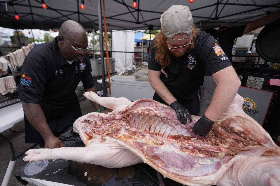 The Shed BBQ and Blues Joint team members Hobson Cherry, left, and James Newell season a whole hog as they compete at the World Championship Barbecue Cooking Contest, Friday, May 17, 2024, in Memphis, Tenn. (AP Photo/George Walker IV)