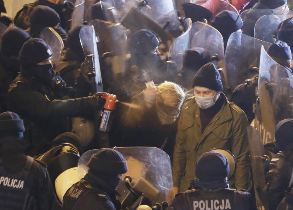 Police use tear gas against an opposition lawmaker, Barbara Nowacka, as protesters block a major thoroughfare in Warsaw, Poland, Saturday Nov. 28, 2020. The police blocked protesters from marching in Warsaw as demonstrations took place across Poland against an attempt to restrict abortion rights and recent use of force by police.(AP Photo/Czarek Sokolowski)