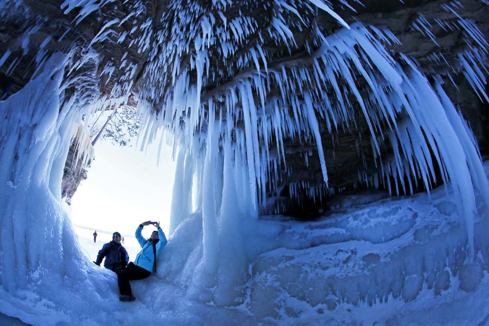 In this Feb. 2, 2014 photo, people take pictures inside a cave at Apostle Islands National Lakeshore in northern Wisconsin, which has been transformed into a dazzling display of ice sculptures by the arctic siege gripping the Upper Midwest. The caves are usually are accessible only by water, but Lake Superior’s rock-solid ice cover is letting people walk to them for the first time since 2009. (AP Photo/The Star Tribune, Brian Peterson) MANDATORY CREDIT; ST. PAUL PIONEER PRESS OUT; MAGS OUT; TWIN CITIES TV OUT