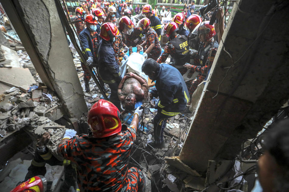 Fire officials rescue an injured person from the debris of a commercial building after an explosion, in Dhaka, Bangladesh, Tuesday, March 7, 2023. An explosion in a seven-story commercial building in Bangladesh's capital has killed at least 14 people and injured dozens. Officials say the explosion occurred in a busy commercial area of Dhaka. (AP Photo/Abdul Goni)