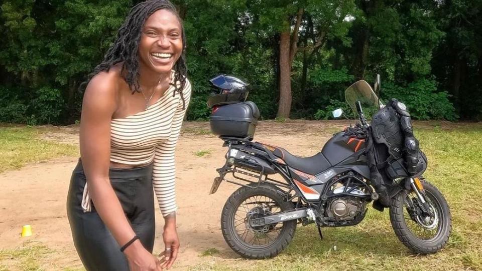     Udoh Ebaide Joy standing in front of her motorcycle 