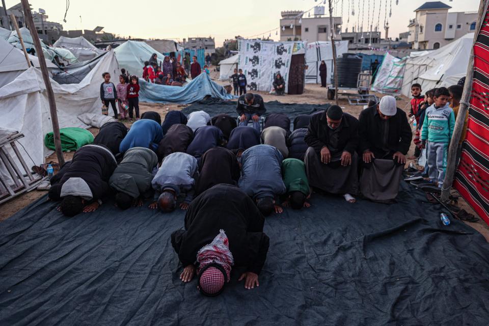 Palestinians pray before breaking the fast on the first day of the Muslim holy fasting month of Ramadan, at a camp for displaced people in Rafah in the southern Gaza Strip on March 11, 2024, amid ongoing battles between Israel and the militant group Hamas.