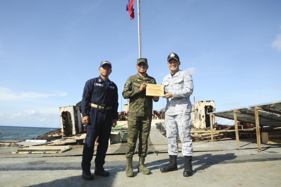 In this handout photo provided by the Armed Forces of the Philippines PAO, Philippine military chief, General Brawner, center, and Vice Admiral Alberto Carlos, right, Commander of the AFP's Western Command poses for pictures during their visit with Filipino marines and navy personnel stationed aboard the long-marooned BRP Sierra Madre at the Second Thomas Shoal, locally known as Ayungin Shoal, at the disputed South China Sea on Sunday Dec. 10, 2023. The Philippine military chief said Monday he was with Filipino forces aboard a supply boat when it was blasted with a water cannon and surrounded and bumped by Chinese coast guard ships over the weekend in the disputed South China Sea. (Armed Forces of the Philippines PAO via AP)