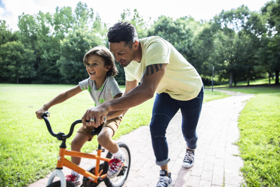 A dad teaching his son how to ride a bicycle