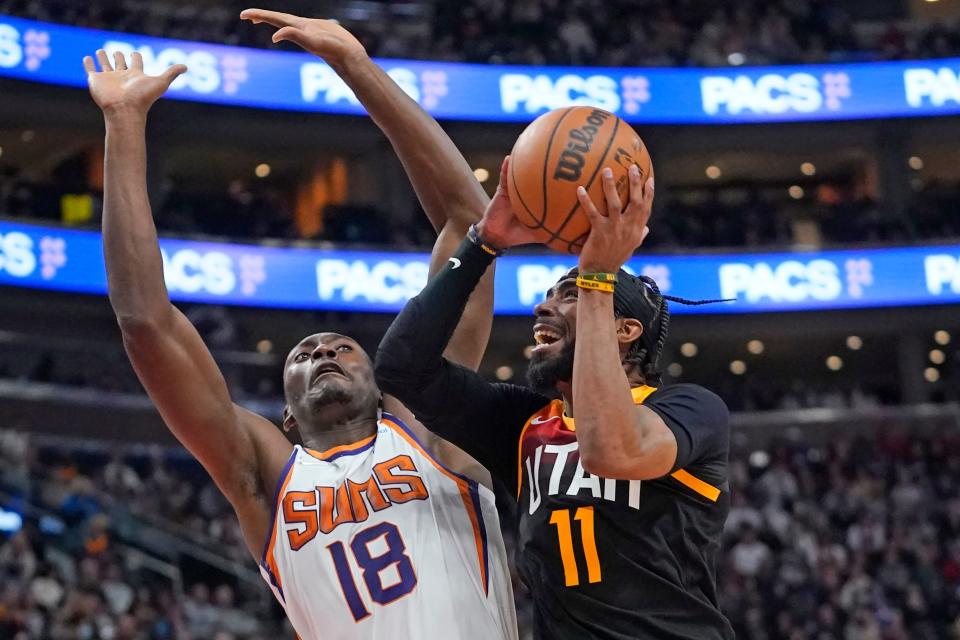 Phoenix Suns center Bismack Biyombo (18) defends as Utah Jazz guard Mike Conley (11) goes to the basket in the first half during an NBA basketball game Wednesday, Jan. 26, 2022, in Salt Lake City. (AP Photo/Rick Bowmer)